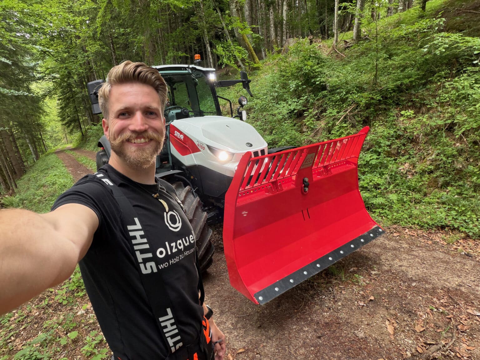 Holzarbeiter neben rotem Polterschild auf Steyr-Traktor im Wald